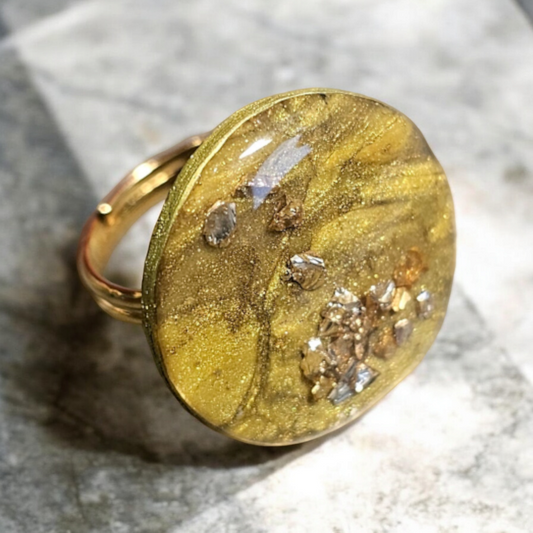bague Orlane en argile polymère, avec un superbe effet pierre dorée. Son anneau réglable en plaqué or 24 carats s'adapte parfaitement à votre doigt, pour un confort optimal. Son diamètre de 2,3 cm