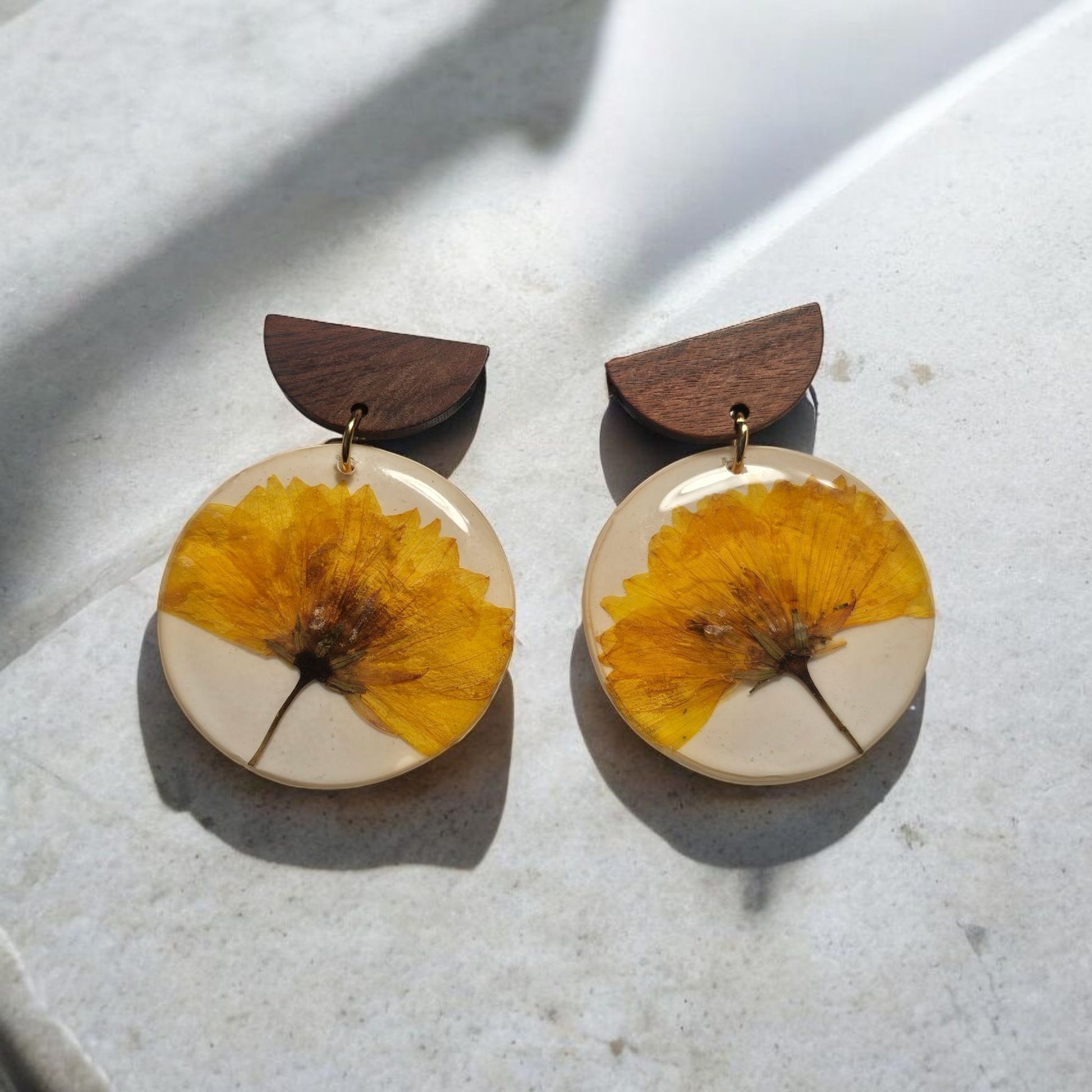 Les boucles d'oreilles Madeleine vous apportent une touche de naturel avec leurs fleurs véritables. Avec une longueur de 5,2cm et des clous en acier inoxydable, elles sont à la fois élégantes et résistantes. Parfaites pour ajouter une touche de charme à votre tenue.