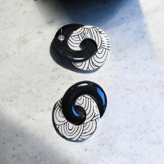 paire de boucles d'oreille rondes noires et blanches de 5 cms. Avec son design élégant, ces boucles d'oreille ajoutent une touche de sophistication à n'importe quelle tenue.