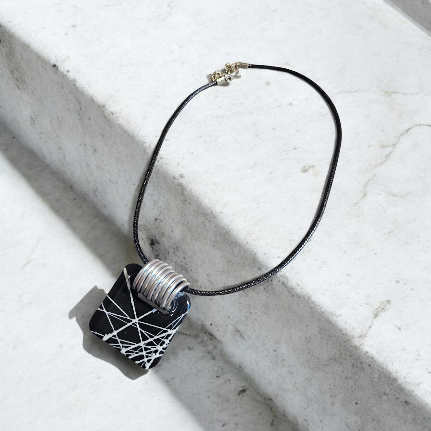 collier en argile polymère noir avec ses traits blancs rappelant la beauté des toiles de la Babouk de l'île de la Réunion. Avec ses dimensions de 3,7 x 3,7 cm