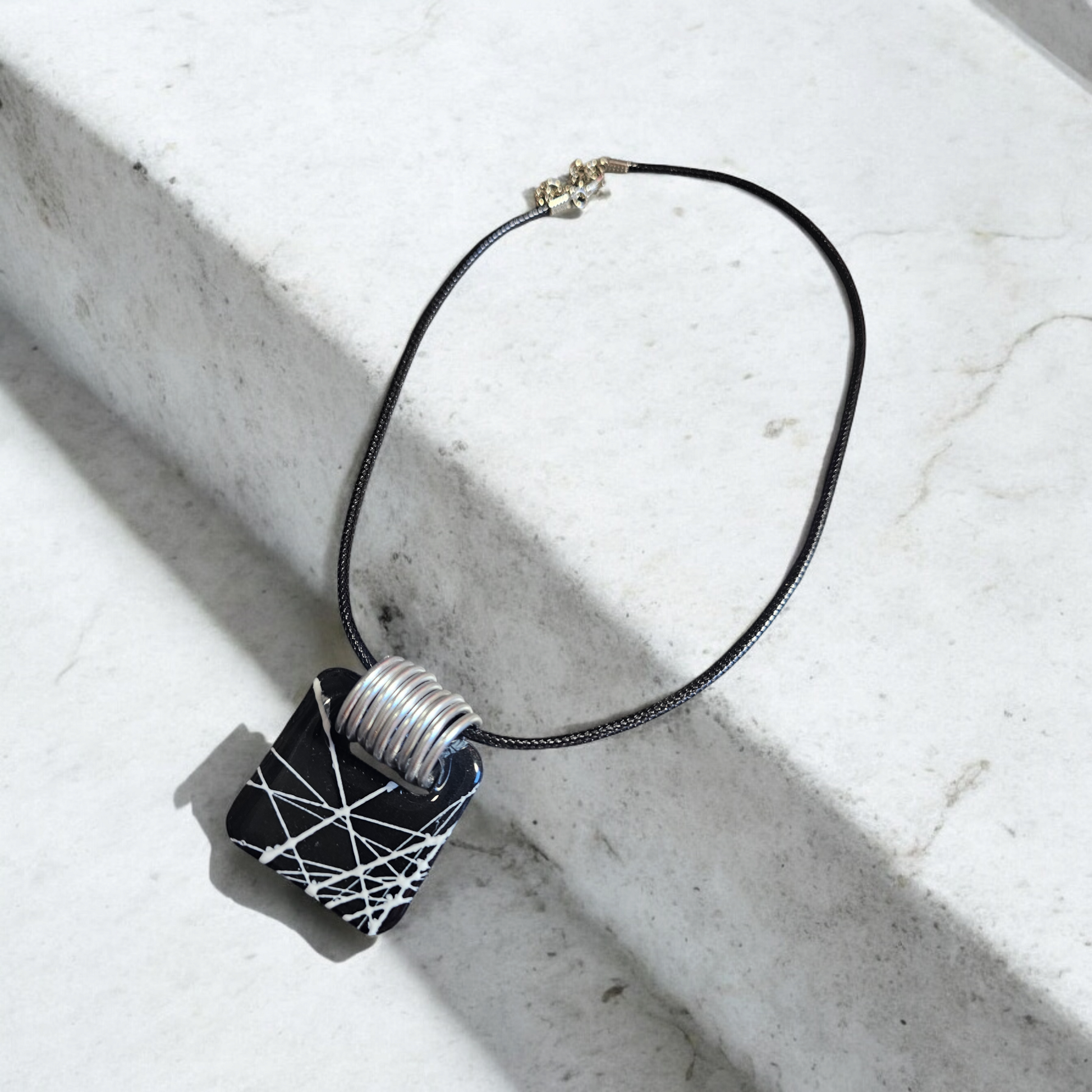 collier en argile polymère noir avec ses traits blancs rappelant la beauté des toiles de la Babouk de l'île de la Réunion. Avec ses dimensions de 3,7 x 3,7 cm