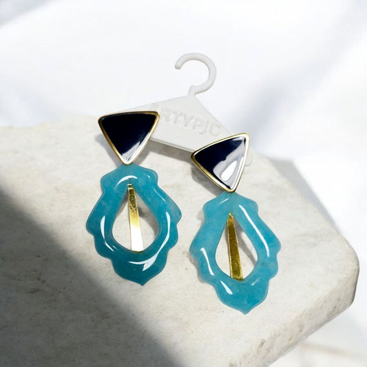 Ces boucles d'oreilles Indigo apporteront une touche d'élégance à votre look. Avec son effet pierre bleue de 5,6 cm, elles sont un accessoire incontournable. Les clous plaqués or 18 carats ajoutent une touche de raffinement supplémentaire.