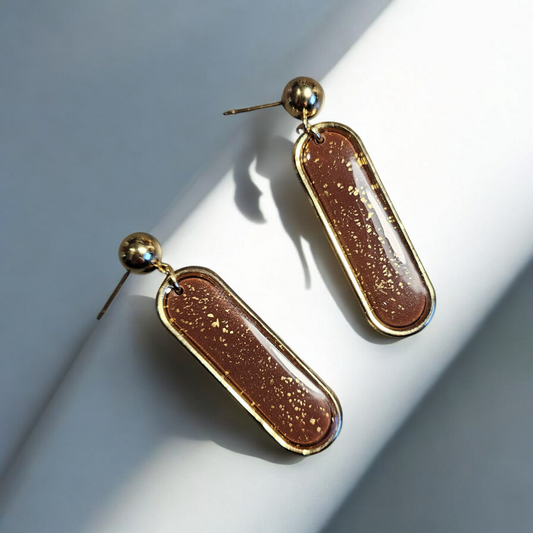 Ces boucles d'oreille élégantes en argile polymère sont un choix luxueux pour compléter votre look. Avec des paillettes dorées et des tiges en acier inoxydable
